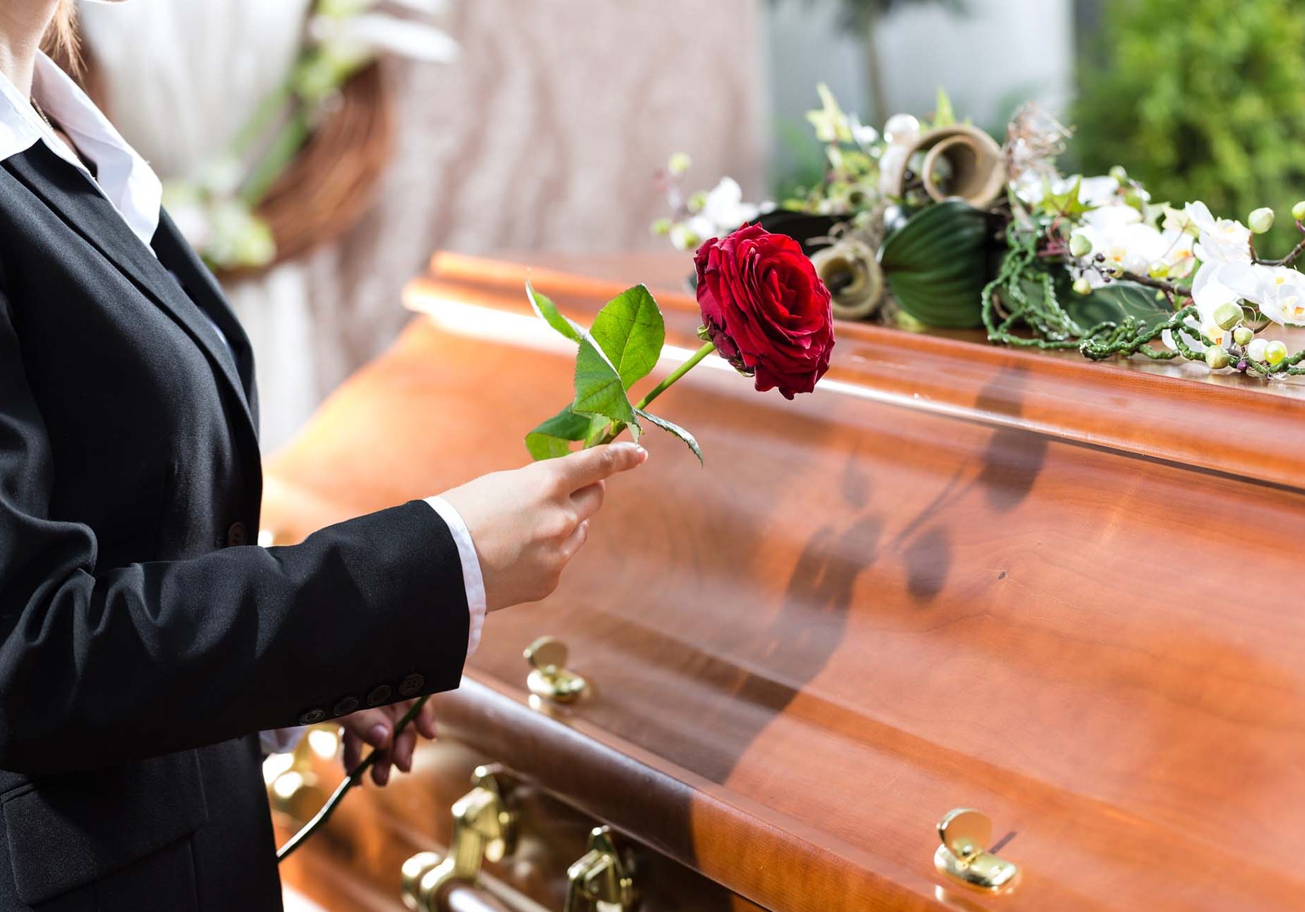 Woman holding a red rose beside a coffin in Falkirk