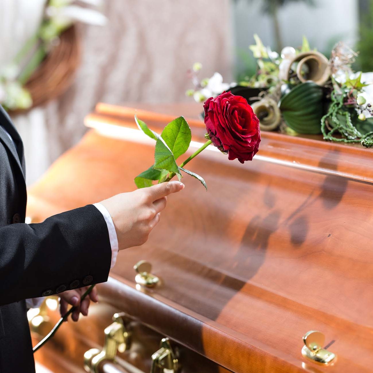 Woman holding a red rose beside a coffin in Falkirk